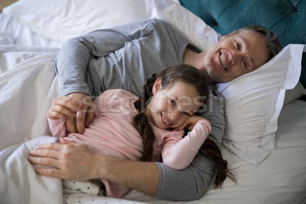 Smiling father and daughter lying on bed in bedroom Stock photo © wavebreak_media