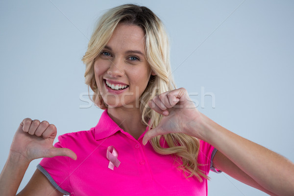 Portrait of happy woman pointing on pink ribbon Stock photo © wavebreak_media