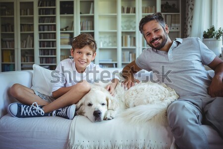 Stock photo: Father and son sitting on sofa with pet dog and playing video games