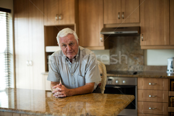 Portrait of senior man sitting with hands clasped in the kitchen Stock photo © wavebreak_media