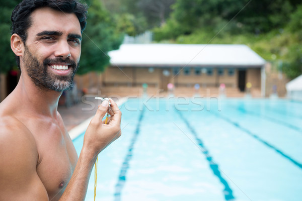 Smiling lifeguard standing with whistle near poolside Stock photo © wavebreak_media