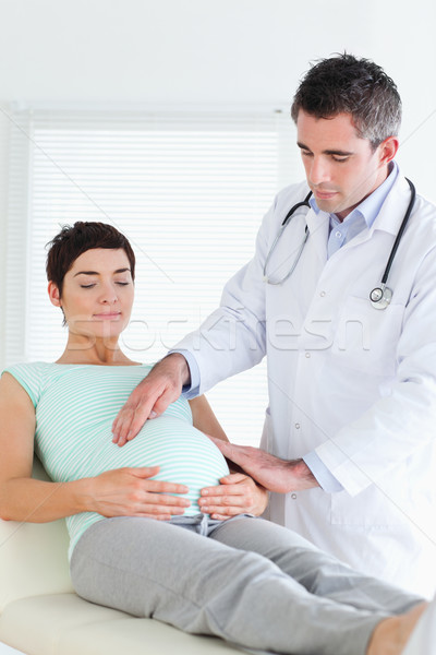Doctor examining the belly of a pregnant woman in a room Stock photo © wavebreak_media