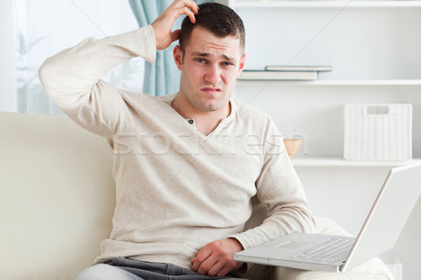 Confused man using a laptop in his living room Stock photo © wavebreak_media