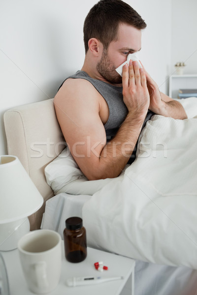 Portrait of a sick man blowing his nose in his bedroom Stock photo © wavebreak_media