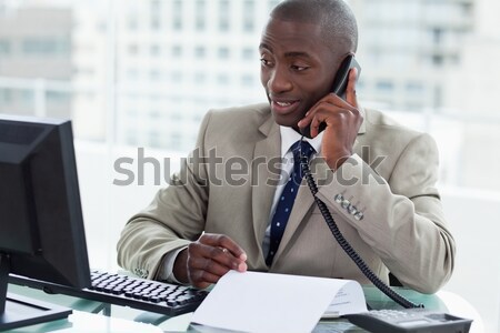 Entrepreneur making a phone call while reading a document in his office Stock photo © wavebreak_media