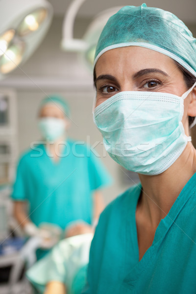 Stock photo: Smiling surgeon standing in front of a colleague in a surgical room