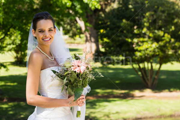Smiling young beautiful bride with bouquet in park Stock photo © wavebreak_media