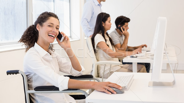 Stock photo: Casual businesswoman in wheelchair on the phone smiling at camer