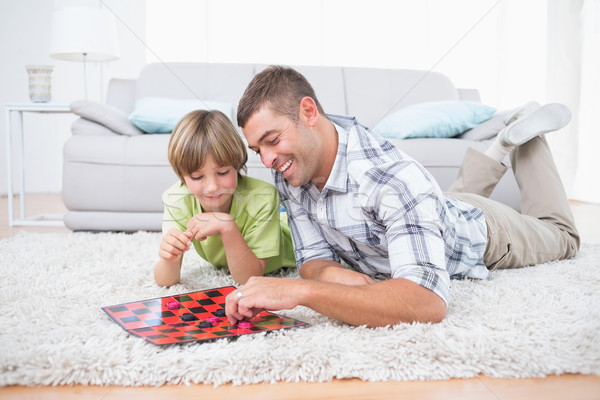 Father and son playing checker game while lying on fur Stock photo © wavebreak_media