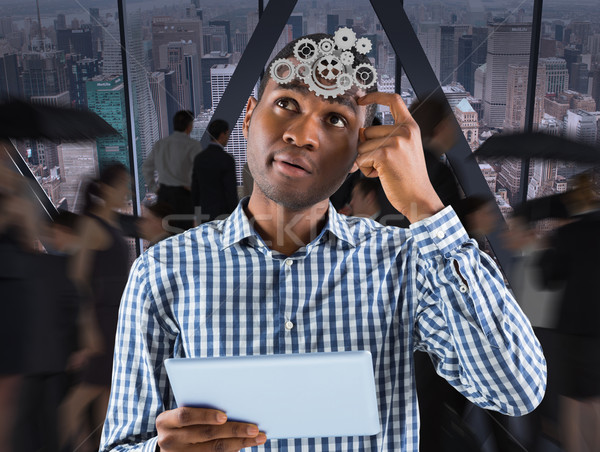 Stock photo: Composite image of young businessman thinking and holding tablet