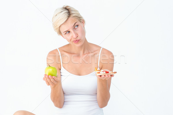 Pretty woman deciding between pizza and apple  Stock photo © wavebreak_media