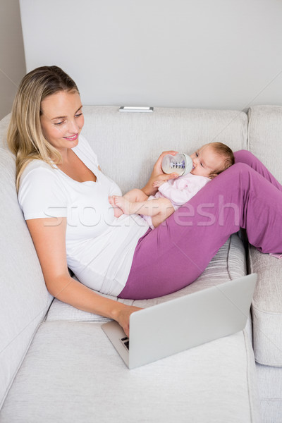 Foto stock: Mãe · usando · laptop · bebê · leite · garrafa