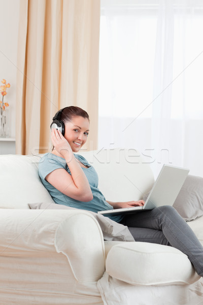 Boa aparência mulher fones de ouvido relaxante laptop sessão Foto stock © wavebreak_media