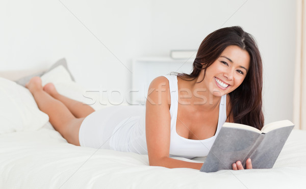 dark-haired woman lying on bed with book in bedroom Stock photo © wavebreak_media