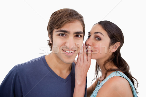 Stock photo: Young woman whispering something to her fiance against a white background