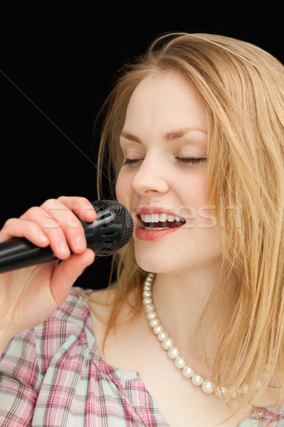 Woman singing while closing her eyes against black background Stock photo © wavebreak_media