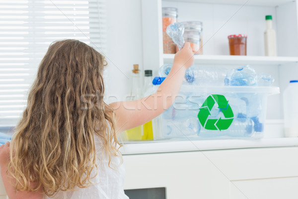 Girl putting plastic bottle in recycling box in kitchen Stock photo © wavebreak_media