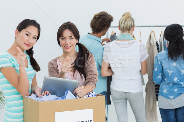 Stock photo: People with clothes donation and digital tablet gesturing thumbs