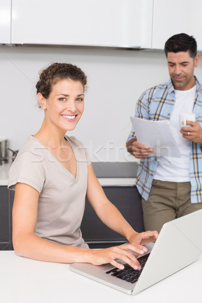 Smiling woman using laptop while partner reads the newspaper Stock photo © wavebreak_media