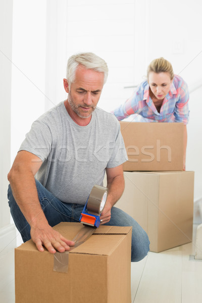 Happy couple sealing cardboard moving boxes Stock photo © wavebreak_media