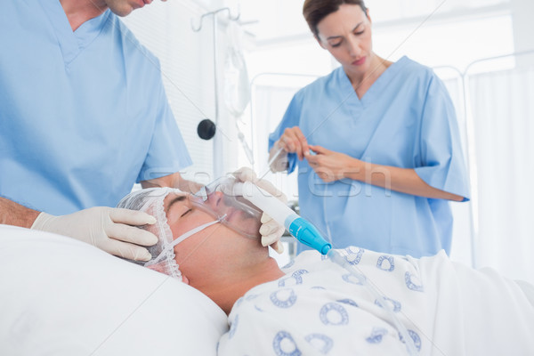 Doctors holding oxygen mask and examining intravenous drip Stock photo © wavebreak_media