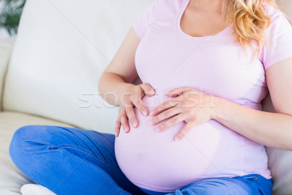 Close up of pregnant woman sitting on couch touching her belly Stock photo © wavebreak_media