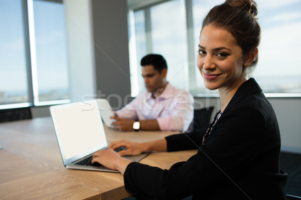 Businesswoman typing on laptop at table with male colleague in background Stock photo © wavebreak_media