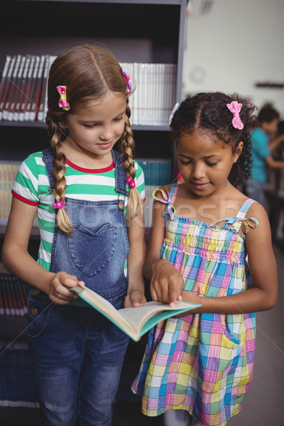 Attentive schoolgirls reading book in library Stock photo © wavebreak_media
