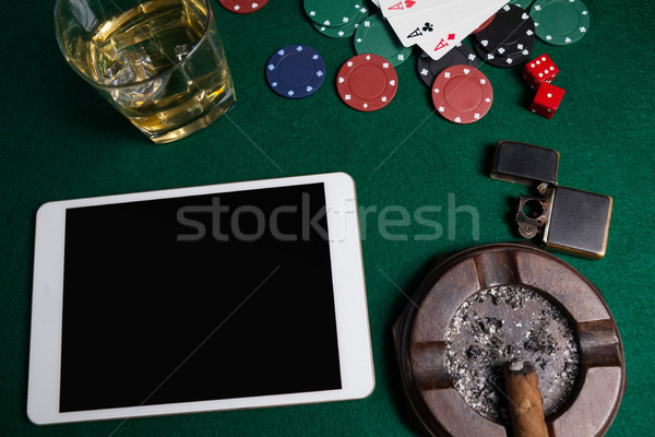 Ashtray, lighter, digital tablet, dice, casino chips and playing cards on poker table Stock photo © wavebreak_media