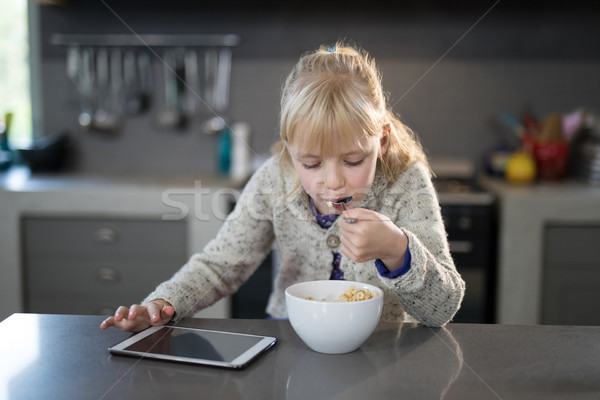 Little girl eating cereals rings with spoon from a bowl Stock photo © wavebreak_media