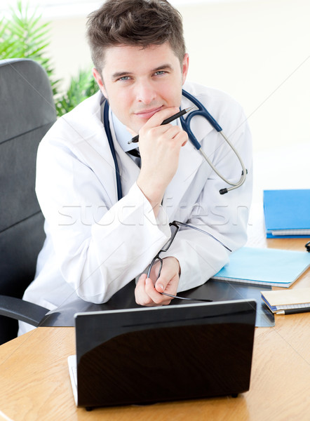 Sorridente médico do sexo masculino usando laptop sessão secretária prática Foto stock © wavebreak_media