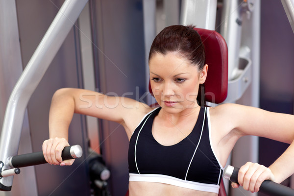 Stock photo: Concentrated athletic woman using a bench press in a fitness center