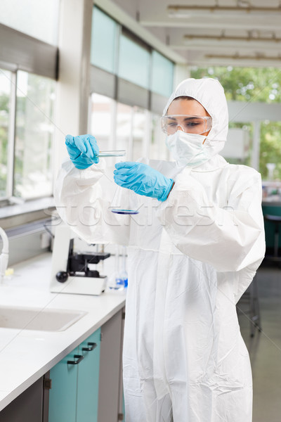 Stock photo: Portrait of a protected scientist pouring liquid in a Erlenmeyer flask in a laboratory