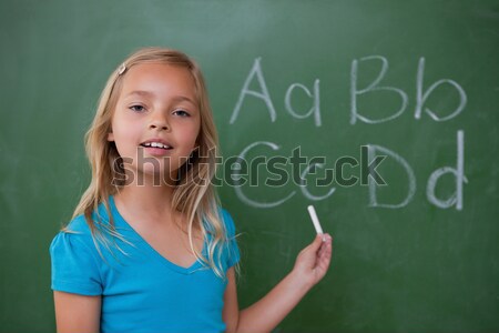 Stock photo: Smiling schoolgirl learning the divisions on a blackground