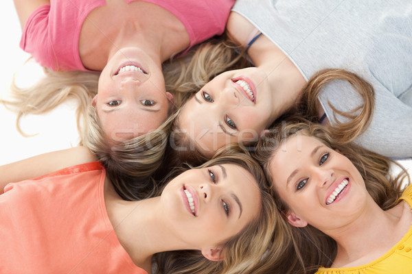 Four smiling girls lying on the ground together with their heads beside one another Stock photo © wavebreak_media