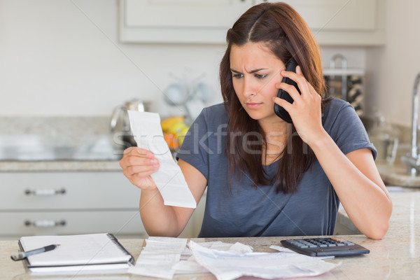Woman calling while calculating bills in kitchen Stock photo © wavebreak_media