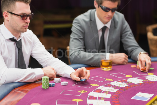 Men sitting at the table wearing sun glasses placing bet Stock photo © wavebreak_media
