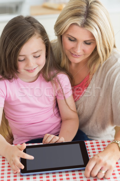 Child using tablet pc with mother at kitchen table Stock photo © wavebreak_media