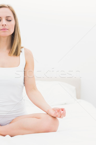 Woman sitting in lotus position with eyes on bed Stock photo © wavebreak_media