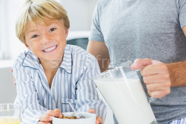 Smiling boy having cereal with father pouring milk Stock photo © wavebreak_media