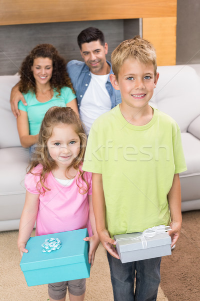 Siblings holding presents in front of parents on the couch Stock photo © wavebreak_media