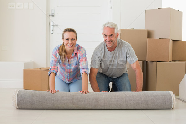 Happy couple rolling out new rug Stock photo © wavebreak_media