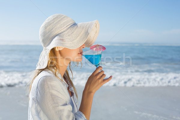 Smiling blonde relaxing by the sea sipping cocktail Stock photo © wavebreak_media