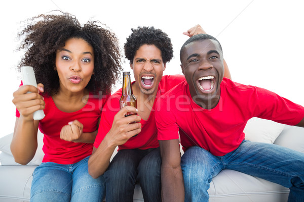 Stock photo: Football fans in red cheering on the sofa with beers