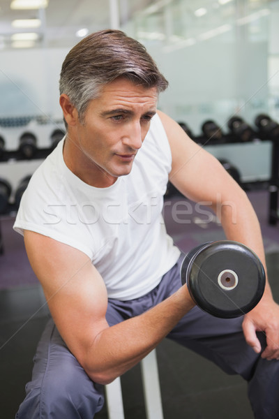 Fit man lifting dumbbells sitting on the bench Stock photo © wavebreak_media