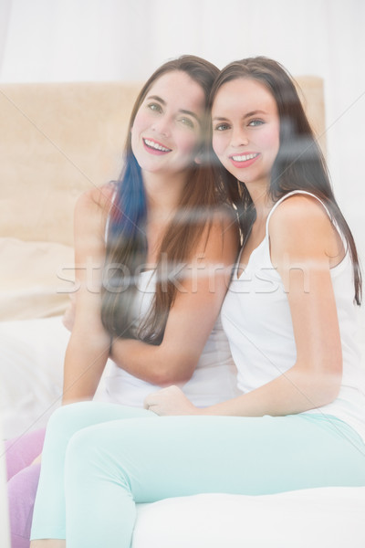 Pretty friends smiling at camera on bed Stock photo © wavebreak_media