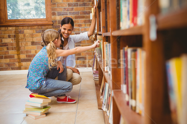 Teacher and little girl selecting book in library Stock photo © wavebreak_media