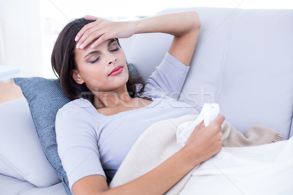 Sick brunette lying on the couch Stock photo © wavebreak_media