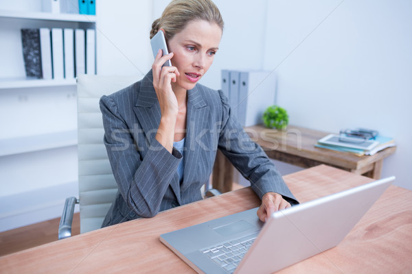 Pretty blonde businesswoman phoning and using her laptop  Stock photo © wavebreak_media