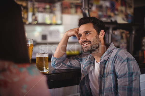 Happy couple interacting while having beer at counter Stock photo © wavebreak_media